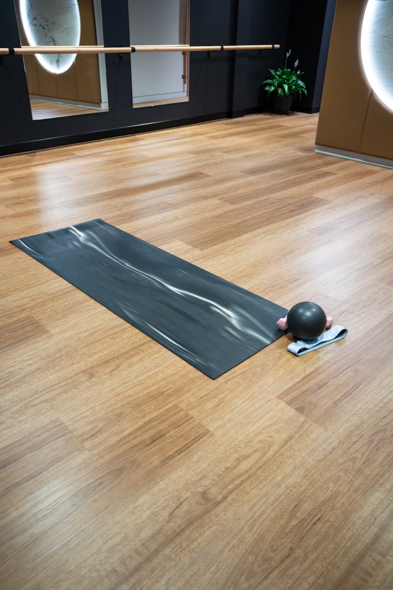 A mat, ball and resistance band set out on the studio floor before a class